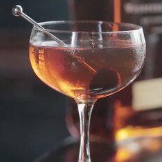 a glass filled with liquid sitting on top of a counter next to bottles and glasses