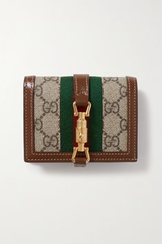 Gucci's 'Jackie 1961' wallet is named after the label's iconic bag - it even has the same gold-tone piston clasp. It's made from hard-wearing coated-canvas printed with the 'GG' monogram and reinforced with brown leather. The striped webbing nods to the label's storied heritage. Gucci Jackie 1961, Canvas Wallet, Gg Monogram, Girly Bags, Card Case Wallet, Gold Clips, Print Coat, Iconic Bags, Brown Coat