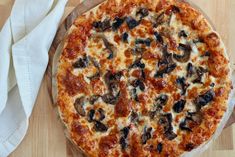 a pizza sitting on top of a wooden cutting board next to a white napkin and fork