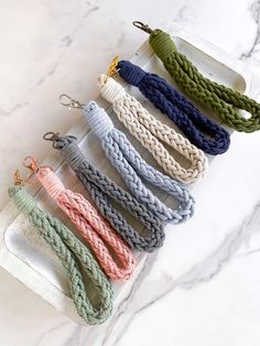 six braided lanyards are lined up on a marble countertop, each with different colors