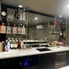 a kitchen with lots of liquor bottles on the counter and shelves filled with alcohol glasses