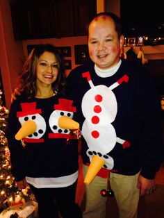 a man and woman standing next to each other in front of a christmas tree wearing ugly sweaters