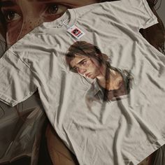 A cool t-shirt featuring a design inspired by The Last of Us, perfect for fans of the game. This unisex heavy cotton tee offers a comfy fit with a classic crew neckline, making it suitable for casual wear. Ideal for gamers and fans of The Last of Us looking for a unique addition to their wardrobe, especially as a gift for birthdays or holidays. Product features - Unisex heavy cotton tee perfect for year-round comfort - Made from strong and smooth fabric, ideal for printing - Classic fit with tea The Last Of Us Ellie, Last Of Us Ellie, Gift Video, The Last, Graphic Print Shirt, Last Of Us, Gamer Gifts, Comfy Fits, Print Shirt