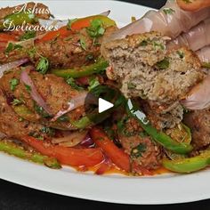 a plate with meat, peppers and onions on it that is being held by someone's hand