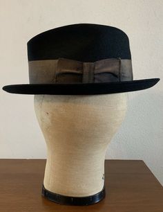 "For your consideration Vintage 60s era CHAMP KASMIR Finish black fedora hat Gold wide grosgrain ribbon 2\" wide Leather sweatband Shows some light dust from storage & minor wear .. couple minor indentions (top crown and large one on side crown) .. interior liner shows age with light dust and soiling , nicely broken in and very handsome! 100% Fur felt Manufacturing tag on inside sweatband Tag marked size 7 1/8 or 57 cm or Medium Shown on vintage size medium mannequin 2.\" brim 4\" crown 6 2/ Classic Black Felt Hat With High Crown, Classic Black High Crown Felt Hat, Classic Black Adjustable Fedora, Black Fitted Fedora With Curved Brim, Fitted Black Fedora With Curved Brim, Black High Crown Fedora For Winter, Black High Crown Fedora For Formal Occasions, Retro Adjustable Fedora Hat Band, Custom Fitted Brimmed Hat