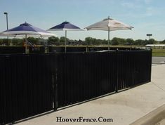 several umbrellas are set up behind a black fence