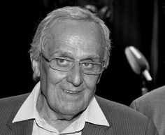 black and white photograph of an older man in suit with glasses smiling at the camera