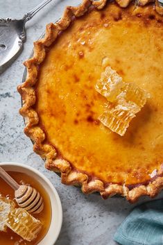 there is a pie with honey on it and a bowl of honey next to it