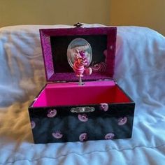 an open pink and black box on a bed