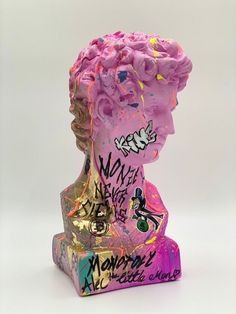 a pink sculpture with graffiti on it's face and head is in front of a white background