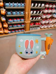 a person holding up a cup with a carrot in it and a cartoon bunny on the side