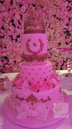 a three tiered cake decorated with pink flowers and a tiara on the top