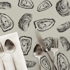 spoons, forks and knives are sitting on a napkin next to an illustration of oysters