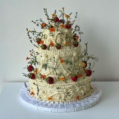 a three tiered wedding cake with strawberries and flowers on the top is decorated in white frosting