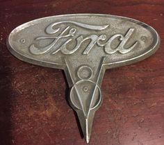 an old ford emblem on a wooden table with the word ford written in cursive font