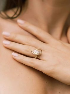 a woman's hand with a gold ring on her shoulder and an oval shaped diamond in the middle