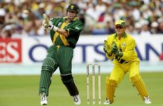 two men in green and yellow uniforms playing cricket