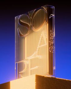 an illuminated sign on the side of a building with blue sky in the back ground