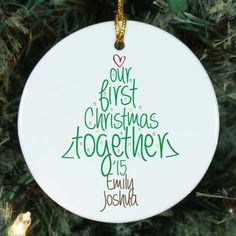 a white ornament hanging from a christmas tree with the words our first christmas together