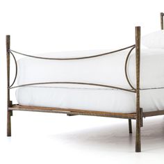 a metal bed frame with white sheets and pillows on it's headboard, against a white background