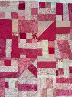 a pink and white patchwork quilt on display