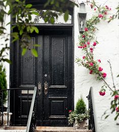 a black door with pink flowers in front of it