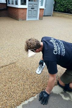 a man in black shirt and gloves working on a driveway with cement paverss