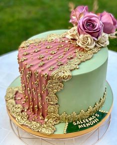 there is a cake that has pink and green frosting on it with gold trimmings