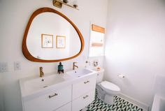 a bathroom with a toilet, sink and mirror in it's corner area on the wall