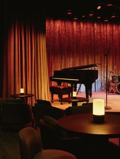 an empty stage with a piano, drums and stools in the background at night