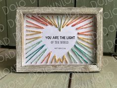 a white frame with colorful crayons in it and the words you are the light of the world