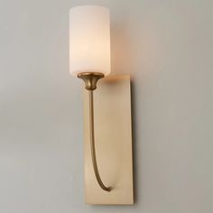 a wall light that is on the side of a wall with a white glass shade