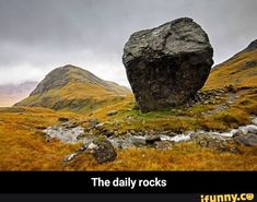 a large rock sitting on top of a lush green hillside