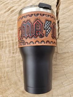 a black and brown leather can holder with the word dad printed on it, sitting on top of a piece of wood