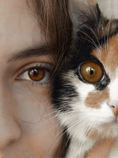 a close up of a person holding a cat's face next to their head