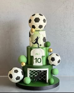 a three tiered cake decorated with soccer balls and an all 10 sign on it