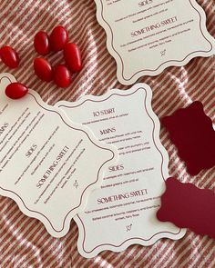 two red hearts are on the table next to each other and some paper cutouts