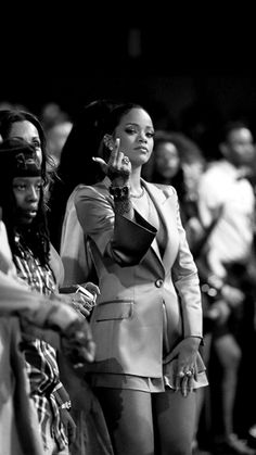 a black and white photo of a woman holding a cell phone in front of a group of people