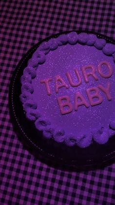 a purple cake with the words tauro baby on it sitting on a checkered table cloth