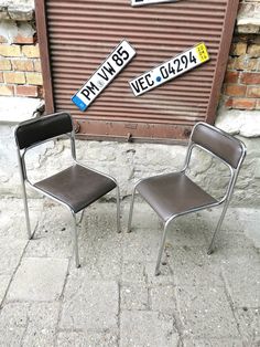 two chairs sitting next to each other in front of a building with street signs on it