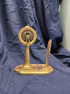 an old fashioned brass clock on a blue cloth