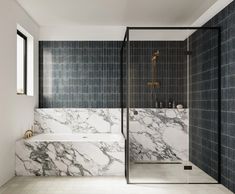 a bathroom with black and white tile walls, flooring and a marble bathtub