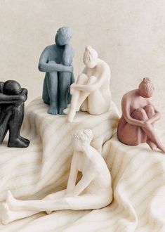 three figurines sitting on top of a bed next to each other in different colors