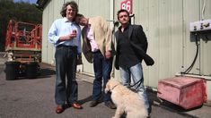 three men and a dog standing in front of a building