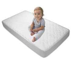 a baby sitting on top of a mattress