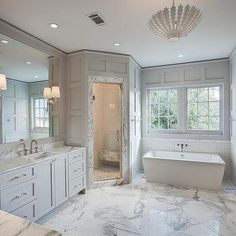 a large bathroom with marble counter tops and white walls, along with two sinks on either side of the bathtub