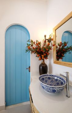 a blue and white bowl sitting on top of a bathroom counter next to a mirror