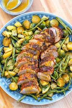 a blue plate topped with meat and veggies on top of a wooden table