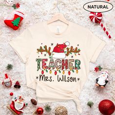 "Teacher Personalized Christmas Shirt, Teacher Custom Xmas Shirt, Teacher Name Shirt Xmas, Teacher Sweatshirt, Teacher Gift, Teacher Santa ↓ See the rest of our trendy collections here ↓ https://www.etsy.com/shop/tranhuynhduc Product Details: 100% Cotton (fiber content may vary for different colors) Medium fabric (5.3 oz/yd² (180 g/m Classic fit Tear away label Runs true to size Care instructions: Machine wash: warm (max 40C or 105F); Non-chlorine: bleach as needed; Tumble dry: medium; Do not ir Christmas Shirts For Teacher, Pre-shrunk White Christmas Shirt, Christmas Cotton Shirt, Cotton Christmas Shirt For Holiday, Christmas Cotton Holiday Shirt, Festive Christmas Cotton Shirt, Christmas Cricut Shirts, Christmas Shirts For Teachers, Teacher Christmas Shirts