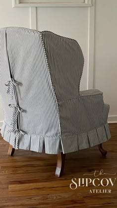 a striped chair with ruffles on it in front of a white wall and wooden floor